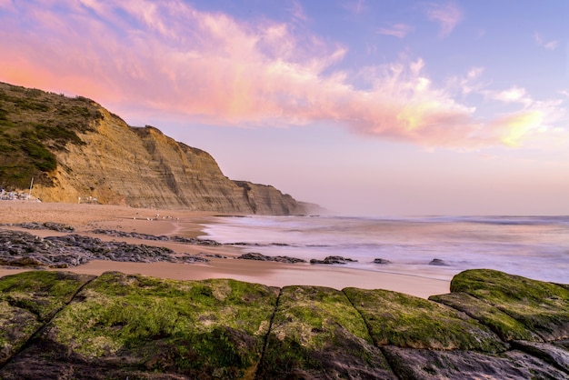 Mesmerizing view of the beach surrounded by rocky mountains during sunset