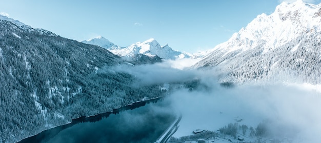 Free photo mesmerizing view of beautiful snow-capped trees with a calm lake under a cloudy sky