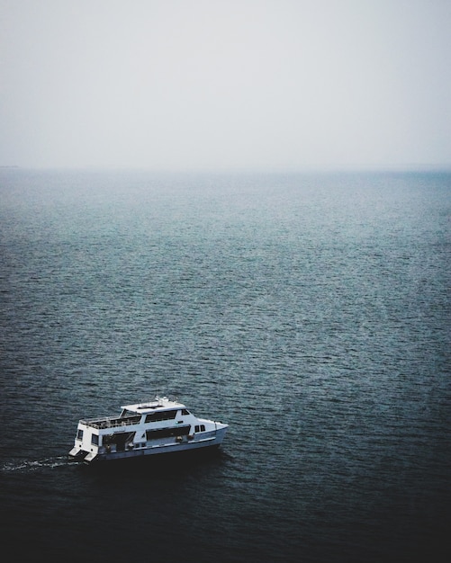 Free photo mesmerizing view of the boat in the calm sea on a foggy day