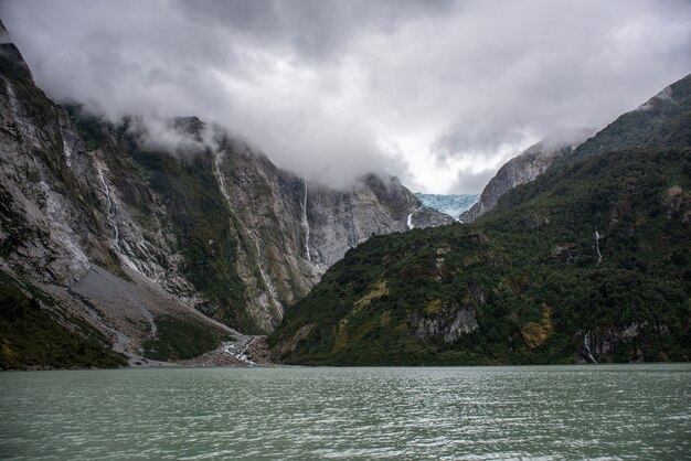 Mesmerizing view of the calm ocean and the rocky mountains with a waterfall