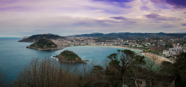 Mesmerizing view of the city along the coastline on a cloudy day with a lush nature