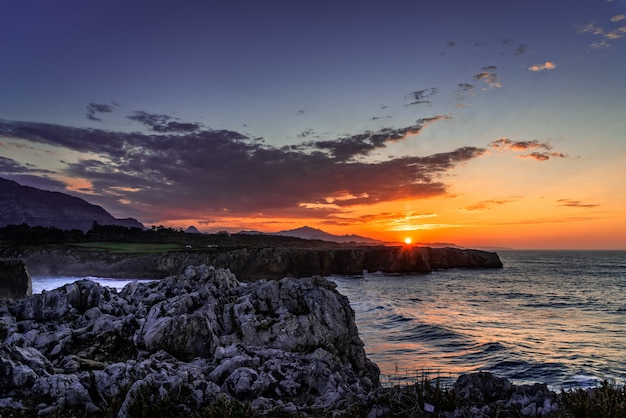 Free photo mesmerizing view of the ocean surrounded by rocky mountains during sunset