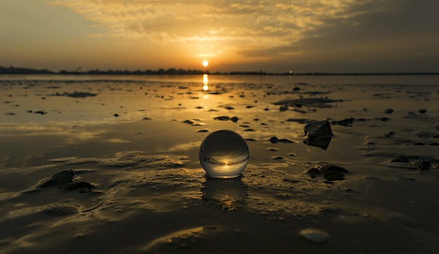 Free photo mesmerizing view of a transparent small ball on the beach captured during the sunset