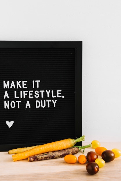 Free Photo message on black card with carrot and tomatoes on wooden table