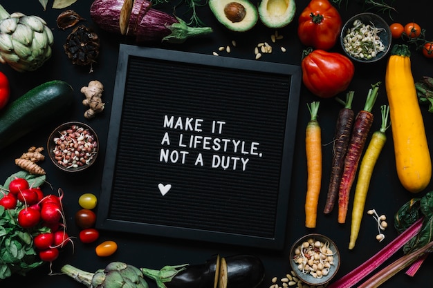 Free Photo message on black frame surrounded with vegetables against black backdrop