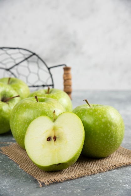 Metal bucket of fresh green apples on marble table. 