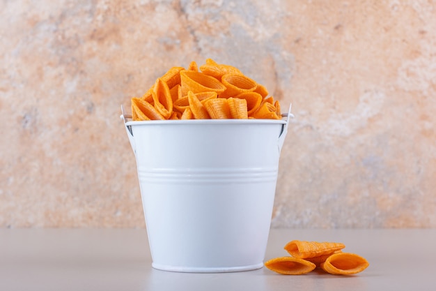 Metal bucket of triangle chips on white background. High quality photo