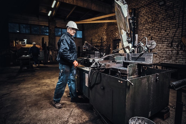 Metal factory operator is controlling machine tool for cutting steel.