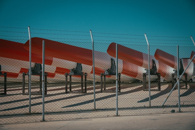 Free Photo metal fence with barb wire and metal canoes behind it with blue sky