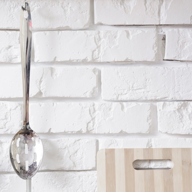 Free photo metal spoon hanging on white brick wall