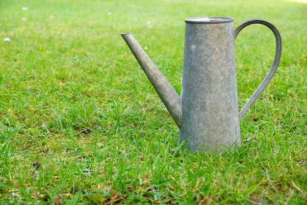 Free photo metal watering can in a grassy field during daytime