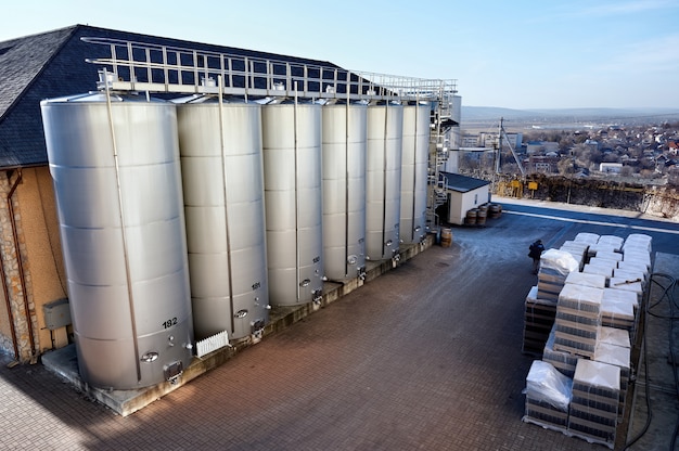 Metal wine storage tanks with dwelling houses on the background in a winery