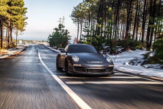 A metallic color mini coupe driving accross the forest.