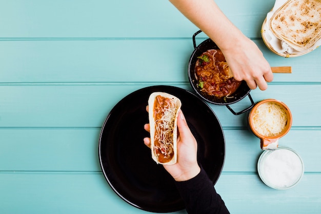 Free photo mexican food concept with hands preparing burrito