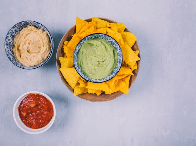 Mexican guacamole dip and nachos tortilla chips with sauce in bowls