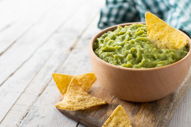 Mexican guacamole with nacho chip in wooden bowl on rustic wooden table Traditional mexican foodxA