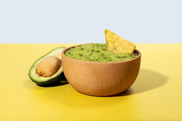 Free photo mexican guacamole with nacho chip on yellow background