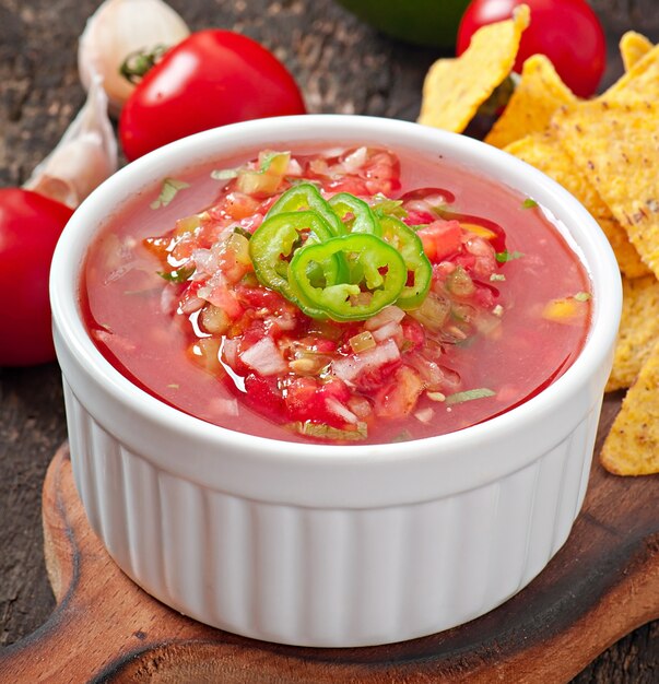 Mexican nacho chips and salsa dip in  bowl on wooden