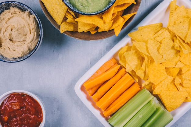 Free Photo mexican nachos chips; carrot with celery stem in tray with salsa sauce in bowl