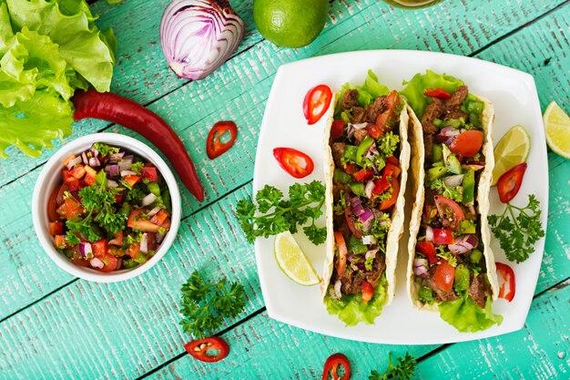 Mexican tacos with beef in tomato sauce and salsa