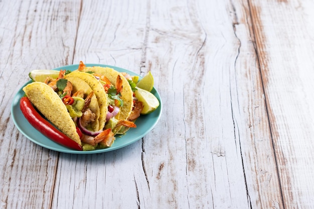 Free Photo mexican tacos with shrimpguacamole and vegetables on wooden table