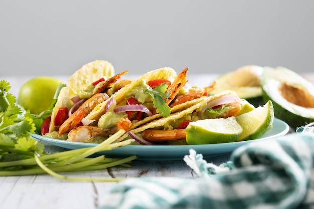 Free Photo mexican tacos with shrimpguacamole and vegetables on wooden table