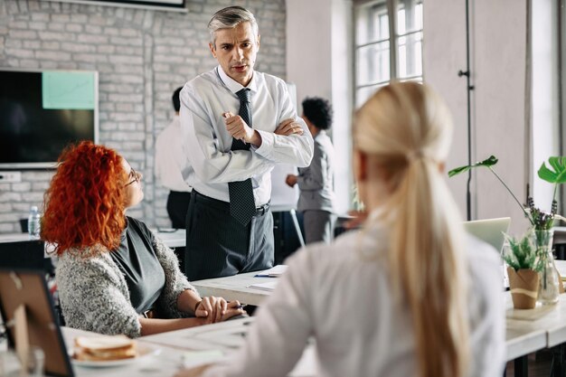 Mid adult businessman discussing with his female colleagues in the office