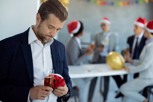 Mid adult businessman feeling sad while being at Christmas party in the office