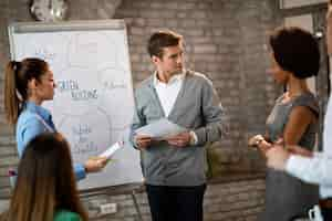 Free photo mid adult businessman and his colleagues brainstorming in front of whiteboard while working on new business strategy in the office