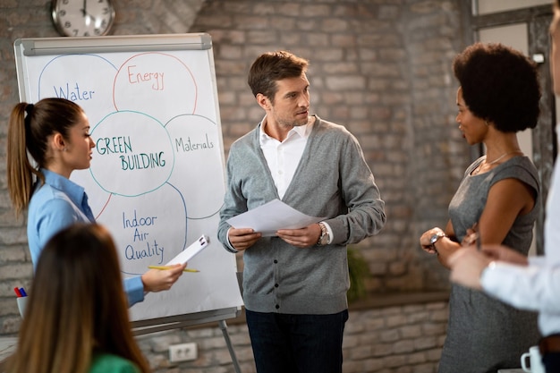 Free Photo mid adult businessman and his colleagues brainstorming in front of whiteboard while working on new business strategy in the office