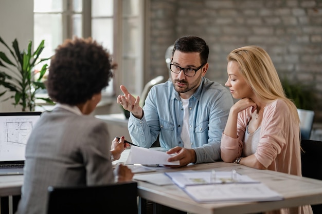 Free photo mid adult couple discussing with financial advisor while analyzing documents on a meeting in the office