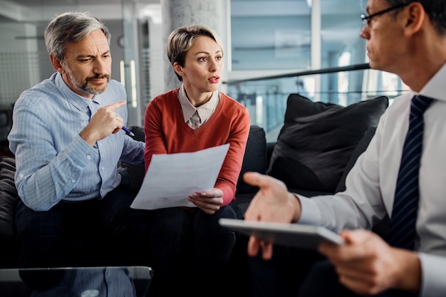 Mid adult couple and their financial advisor discussing about paperwork during the meeting