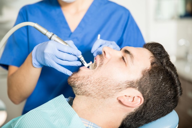 Free photo mid adult man receiving dental treatment from female dentist in clinic