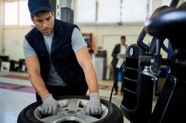 Mid adult mechanic working with car tire in auto repair shop