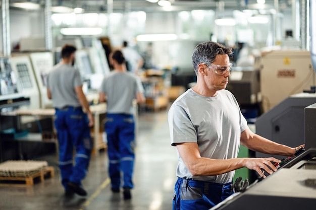 Free Photo mid adult worker operating a cnc machine while working in industrial facility