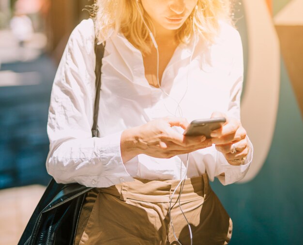 Mid section of a blonde young woman using cellphone at outdoors