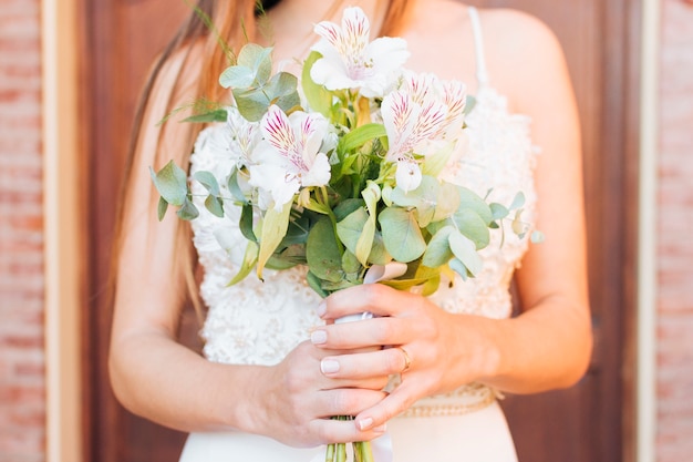 Mid section of a bride's hands holding beautiful flower bouquet