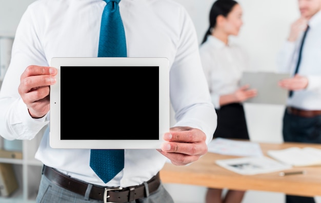 Mid section of a businessman showing blank screen digital tablet at workplace