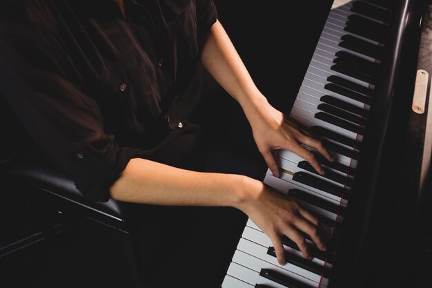 Mid-section of female student playing piano