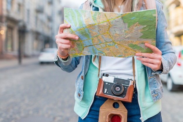 Free Photo mid section of a female traveler with camera holding map in hand