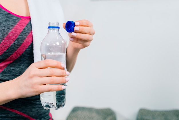 Mid section of fitness young woman's hand holding transparent plastic water bottle