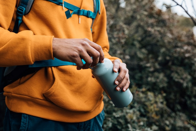 Mid section of a man opening the lid of water bottle