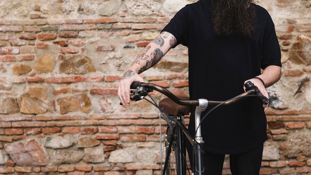 Free photo mid section of a man standing with bicycle against wall