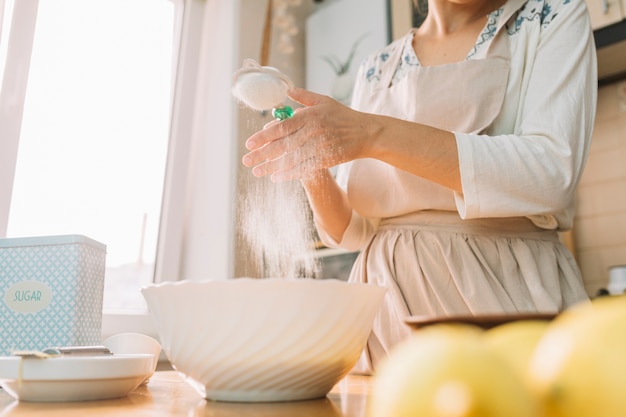 Mid-section of a woman in a kitchen prepares dough from flour to make pie