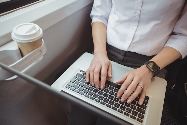 Mid-section of woman using laptop