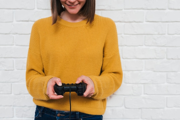 Free photo mid section of a young woman playing the video game with joystick