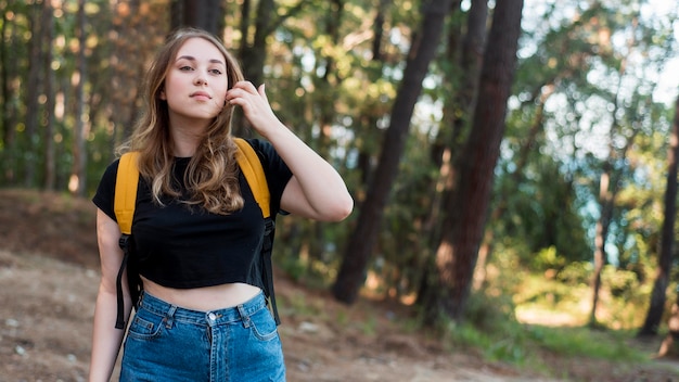 Free photo mid shot blonde girl with backpack in forest