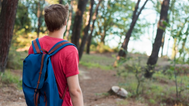 Free photo mid shot boy with backpack in forest