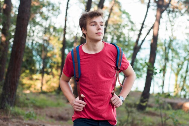 Mid shot boy with backpack in woods