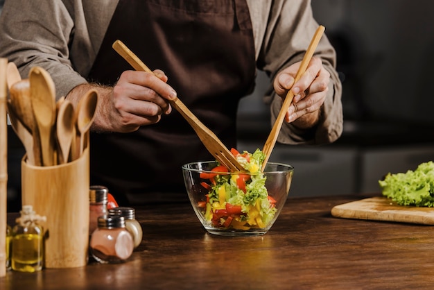 Free photo mid shot chef mixing salad ingredients